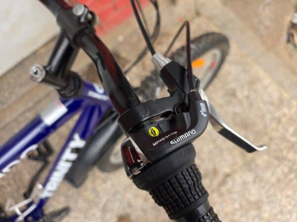 Close-up of mountain bike handlebar with Shimano gear shifter and brake lever.